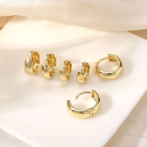 Detailed set of three golden hoop earrings in small, medium, and large sizes on silk cloth