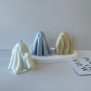 Three-piece set of ghost-shaped candles in white, light blue and yellow on white stand