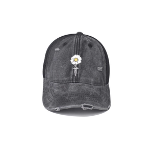 Close-up of distressed denim baseball cap with Blessed text and white daisy embroidery