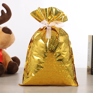 Détail du sac cadeau doré avec motif flocons laser et ruban de serrage blanc