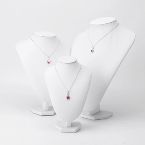 Silver necklace with red gemstone pendant on white mannequin stand for jewelry display