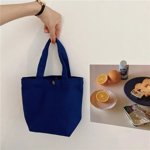Macro detail of navy canvas lunch bag with metal snap closure and reinforced handle