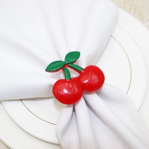 Macro shot of red cherry napkin ring with green leaves on white plate and fabric