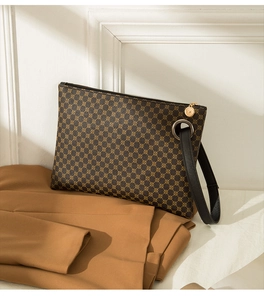 Close-up of vintage brown patterned clutch bag with black leather strap and metal ring