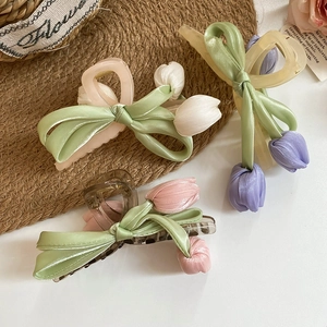 Detail view of handmade tulip hair clips with fabric flowers on woven mat background