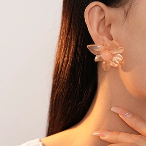 Close-up of translucent pink resin floral stud earrings with glossy multi-layered petals