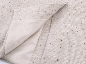 Gros plan du tissu d'un blazer en tweed beige montrant la maille et la doublure lisse