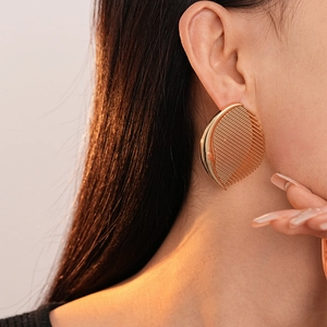 Macro detail of gold-plated comb-shaped earrings with vertical stripes on ear lobe