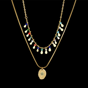 Detail of layered gold necklace with colorful beads and textured starburst pendant