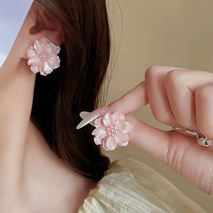 Vue détaillée de boucles d'oreilles fleurs roses avec perles portées à l'oreille
