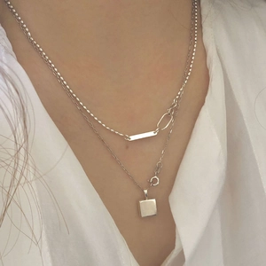 Double-layered S925 silver necklace with square and bar pendants on white shirt