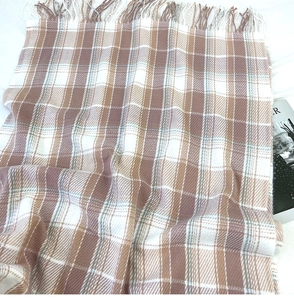 Detail of soft cashmere-like earth tone plaid scarf with elegant fringed edges