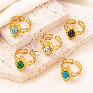 Detailed macro view of bohemian open rings with colorful gemstones on a beige stone surface