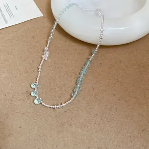 Double-layered beaded necklace with light blue teardrop pendants on a ceramic plate