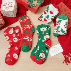 Vier Paar flauschige Weihnachtssocken mit festlichen Motiven in einer Geschenkbox