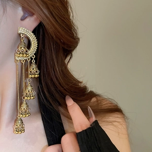 Détail de boucles d'oreilles Jhumka vintage dorées avec glands et cloches sur modèle