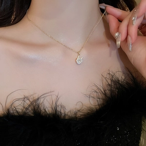 Detail of luxury gold necklace with sparkling zircon pendant worn with black feather outfit
