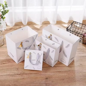 Set of four premium white gift bags with silver feather prints and satin ribbon handles
