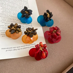 Flat lay detail of vintage shell and tiger eye stone flower stud earrings in three colors