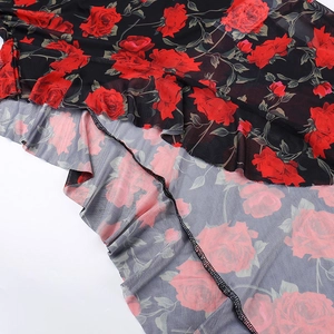 Dettaglio del tessuto in rete floreale con rose rosse e bordi delicati a balze sottili