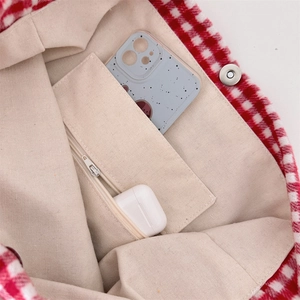 Detail view of plaid tote bag interior with magnetic buckle and practical zipper pocket
