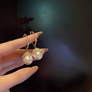 Close-up of gold pearl earrings with sparkling rhinestones and french vintage design