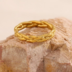 Close-up of 18K gold-plated braided rope ring displayed on a natural rock surface