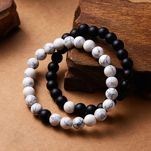 Close-up of 8mm volcanic stone and white turquoise bead bracelets on a wood base