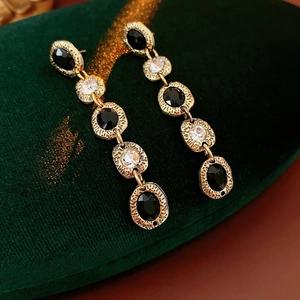 Détail de boucles d'oreilles dorées vintage avec pierres noires sur écrin velours