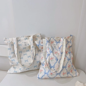 Detail of canvas tote bags featuring blue bow and pink rose floral patterns