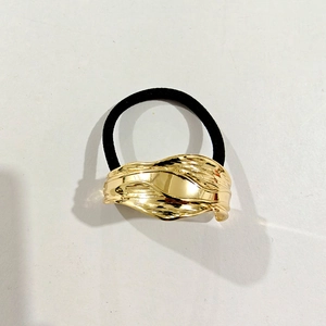 Detailed view of elastic hair tie with textured golden metal accent on white background
