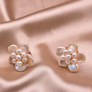 Elegant natural pearl flower earrings on champagne silk fabric background for women