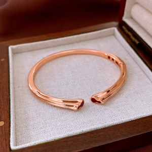 Détail du bracelet ouvert en or rose dans un coffret en bois avec doublure en lin blanc