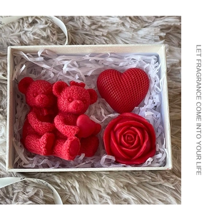 Top view of a red rose bear and heart candle gift box set on a plush background