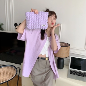 Detail of the purple bubble texture canvas cosmetic bag held by a model in casual setting