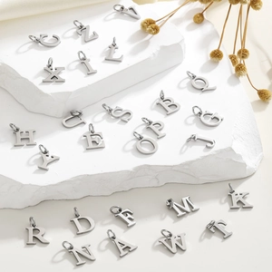 Macro shot of 26 hollow heart initial pendants on stone surface for DIY jewelry