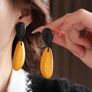 Close-up of model wearing irregular water drop wooden earrings in black and yellow