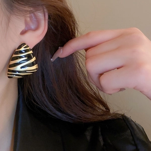 Close-up of geometric triangle earrings with black and gold zebra pattern on model