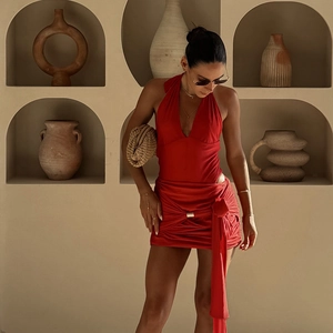 Red halter bodysuit with matching wrap mini skirt styled against a minimalist backdrop