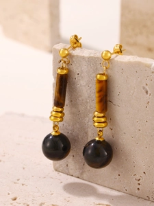 Detail of vintage gold-plated drop earrings featuring natural tiger eye and dark spheres