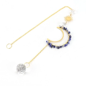 Detail of crystal suncatcher with golden moon frame, blue stones and faceted glass prism