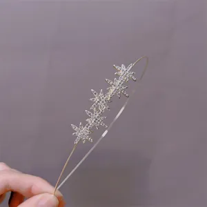 Detail showing high-quality gold headband with sparkling rhinestone stars held in hand
