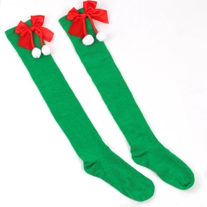 Detailed view of green Christmas over-knee socks with red bows and white pompoms