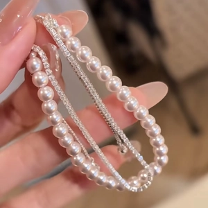 Detail of layered pearl and zircon bracelets showing white round pearls and tennis chains