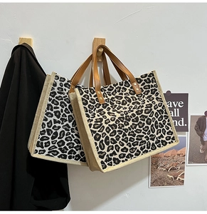Detail of leopard print jute tote bags with leather handles hanging on wooden hooks
