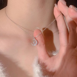 Close-up of a crescent moon pendant necklace with pavé zircons on a delicate chain