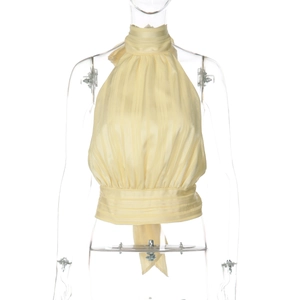 Detail of light yellow pleated halter top showing vertical textures and elegant high neck