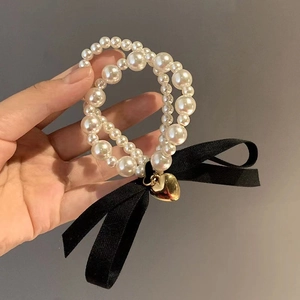 Elegant double-layer pearl bracelet hair tie with black fabric bow and gold heart charm