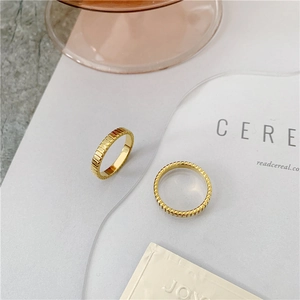 Detail view of two gold titanium steel rings with textured grosgrain vertical ribbing