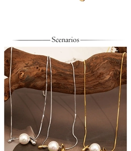 Close-up of gold and silver snake chain necklaces with pearls hanging on wood